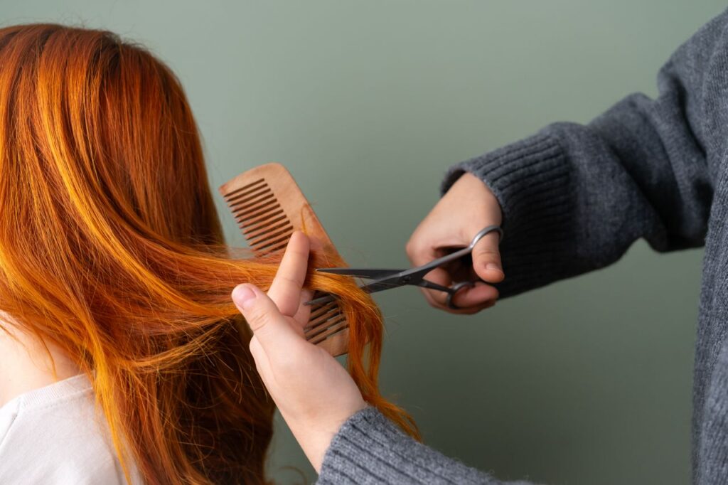 The Art of Drawing Readers In: Your attractive post title goes here Close-up of red hair being trimmed with scissors and comb on green background.